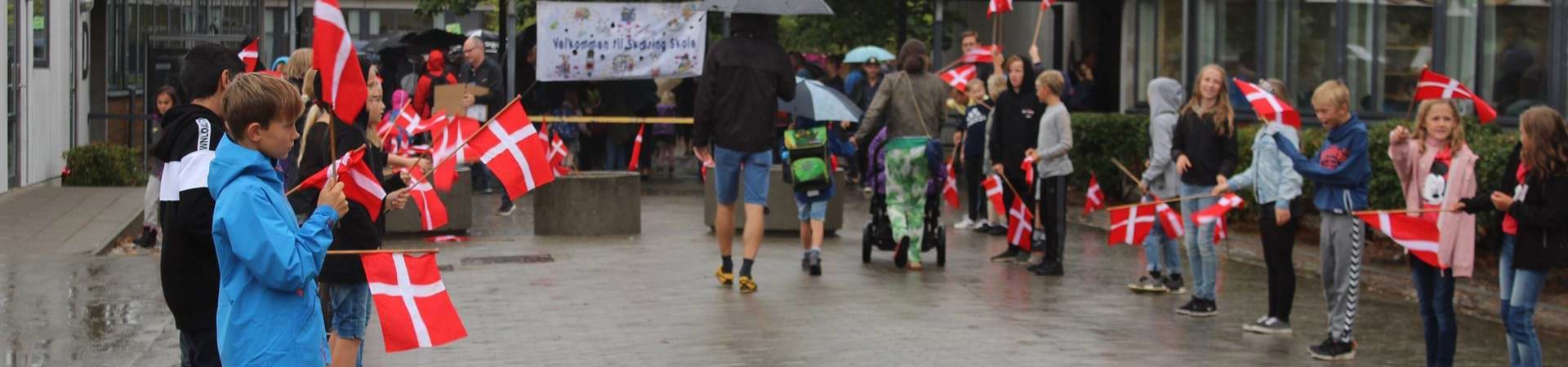 Elever med flag foran indgangen til Skæring skole