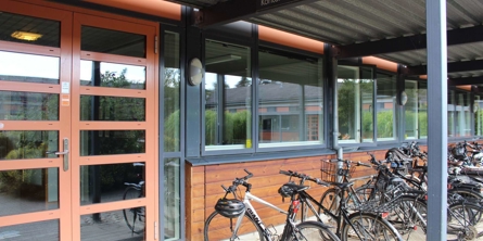 Indgangsdøren til skolens kontor med cykler udenfor