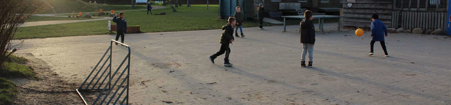 Drenge spiller fodbold i skolegården om vinteren